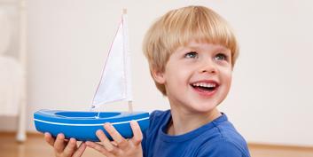 Smiling boy with a toy sailboat