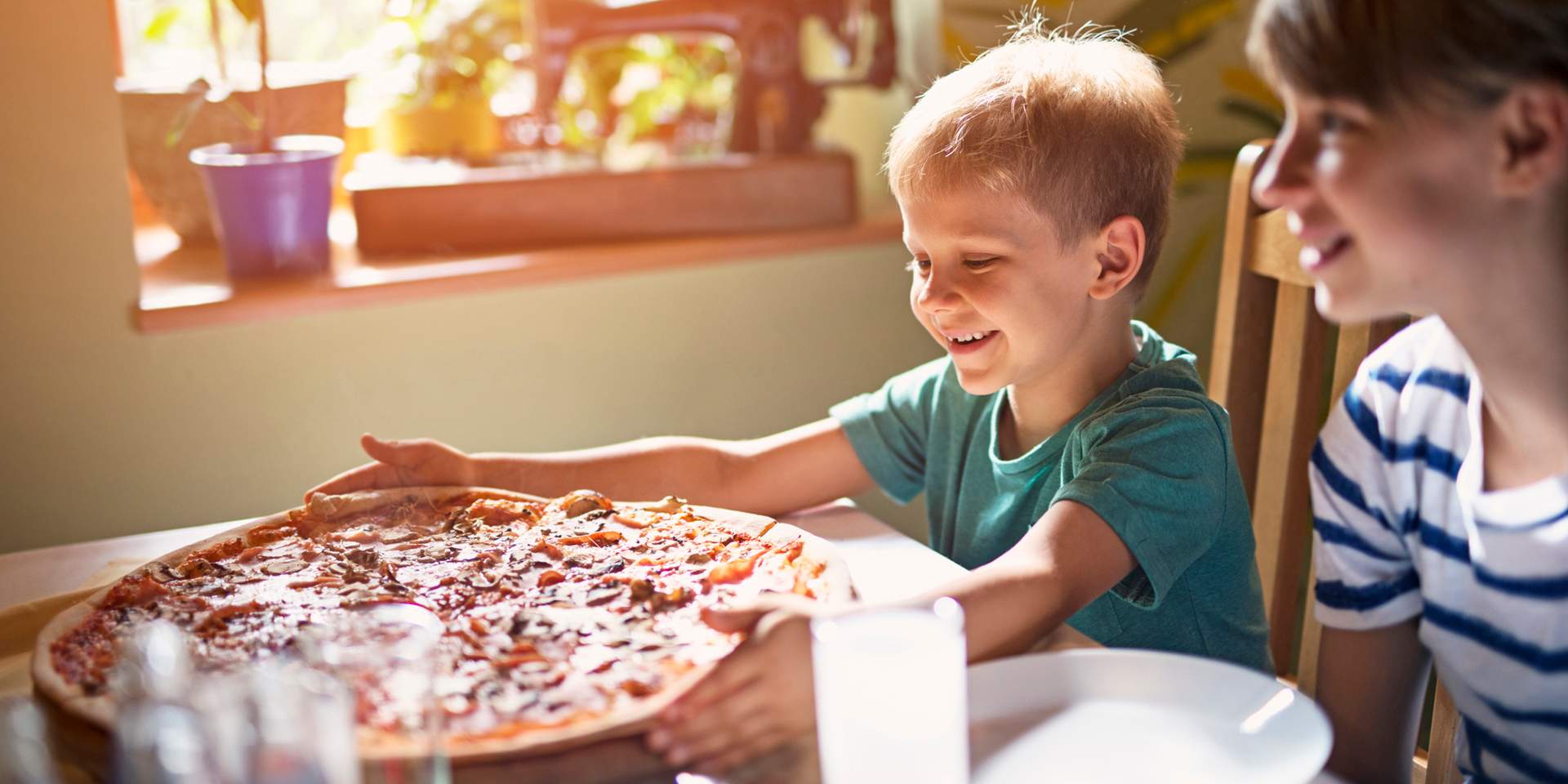Kind greift nach Pizza