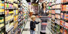 Child walking down supermarket aisle with mom